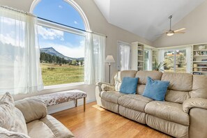 A living room with a large window, a sofa, a lamp, and a ceiling fan.