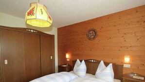 Une chambre à coucher avec une tête de lit en bois, un lit avec une literie à rayures, deux tables de chevet avec des lampes et une armoire en bois.