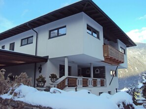 A two-story house with a balcony, a covered porch, and a view of mountains.
