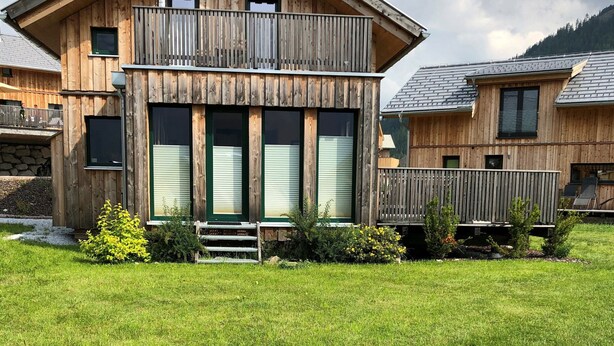 A two-story wooden cabin with a balcony, large windows, and a well-maintained lawn. - Chalet in Hohentauern With Sauna Near ski Area (Hohentauern)