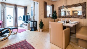 A cozy living room with a TV, seating, and a dining area with a table set for two. - Chalet in Hohentauern With Sauna Near ski Area (Hohentauern)