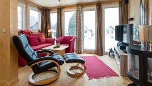 A cozy room with a red sofa, black leather chairs, a wooden coffee table, and a fireplace. - Chalet in Hohentauern With Sauna Near ski Area (Hohentauern)