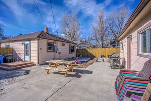 Un patio trasero con una mesa de picnic, una parrilla y una valla de madera.