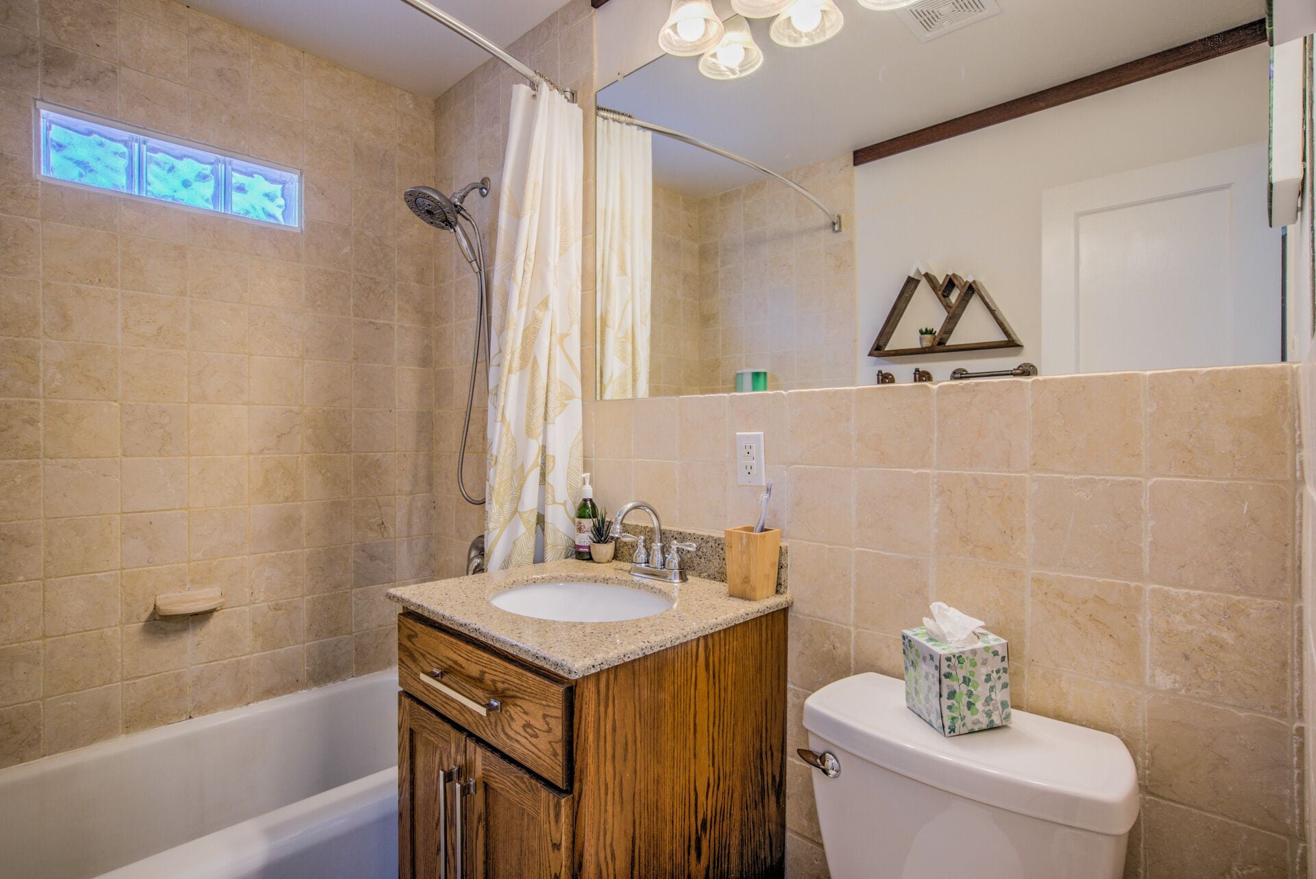 A bathroom with a wooden vanity, a white toilet, and a shower with a curtain.