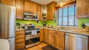 A kitchen with wooden cabinets, stainless steel appliances, and a window with blinds. - Stir Crazy! Bike Trails, Dogs OK, Food & Nightlife (Colorado Springs)