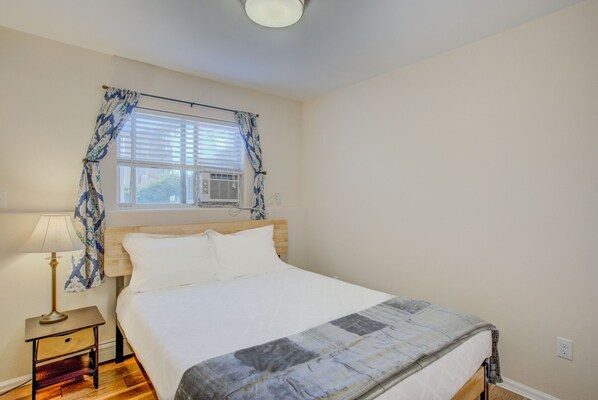 A bedroom with a bed, a nightstand, a lamp, and a window with curtains.