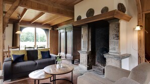 A cozy living room with a fireplace, a sofa, a coffee table, and a chair. - Farmhouse in Enschede Near Forest (Enschede)