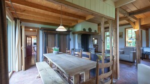 A rustic dining area with a wooden table and benches, a stone fireplace, and a view of the outdoors. - Farmhouse in Enschede Near Forest (Enschede)