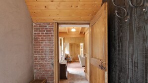 A wooden door leading to a room with a brick wall and a woven basket on the floor. - Farmhouse in Enschede Near Forest (Enschede)