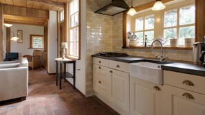 A kitchen with white cabinets, a black countertop, and a window with a view of trees. - Farmhouse in Enschede Near Forest (Enschede)
