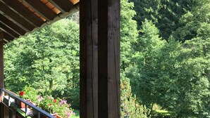 Un balcon en bois offrant une vue sur une forêt verdoyante et luxuriante.