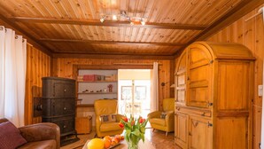 A cozy wooden interior with a sofa, yellow armchairs, a wooden cabinet, and a table with fruit and flowers. - Eichenborn Gartenaufenthalt (Bad Pyrmont)