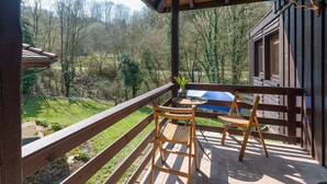 A wooden deck with a table and chairs, overlooking a forested landscape. - Eichenborn Gartenaufenthalt (Bad Pyrmont)