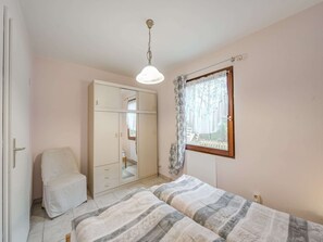 Ett sovrum med en säng, en garderob, en stol och ett fönster med utsikt över träd.