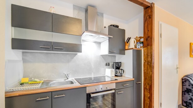 A modern kitchen with grey cabinets, a stainless steel stove, and a coffee maker. - Gartenbungalow in Blankenfelde-mahlow (Blankenfelde-Mahlow)
