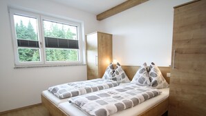 A bedroom with a wooden bed, a window with blinds, and a wardrobe. - Apartment in Annaberg Near Dachstein Ski (Annaberg-Lungoetz)