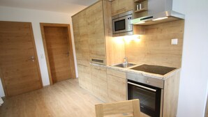 A compact kitchen with wooden cabinets, a built-in microwave, a stainless steel sink, and an oven. - Apartment in Annaberg Near Dachstein Ski (Annaberg-Lungoetz)