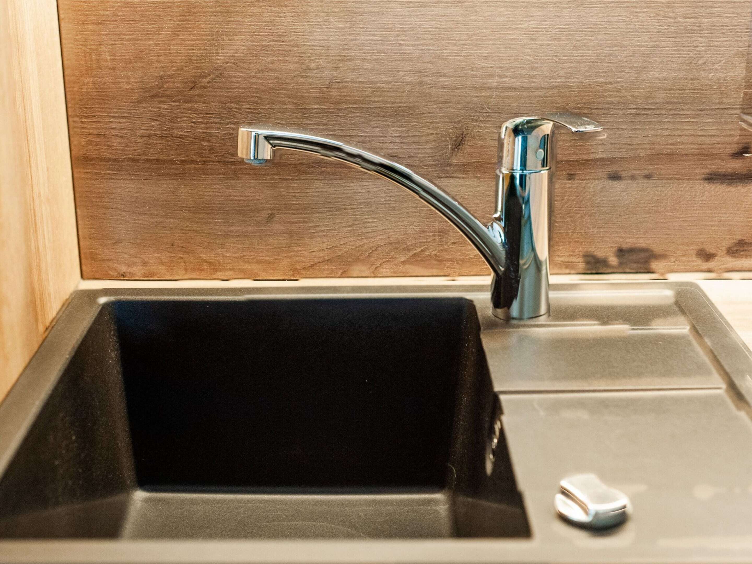 A kitchen sink with a chrome faucet and a black basin.