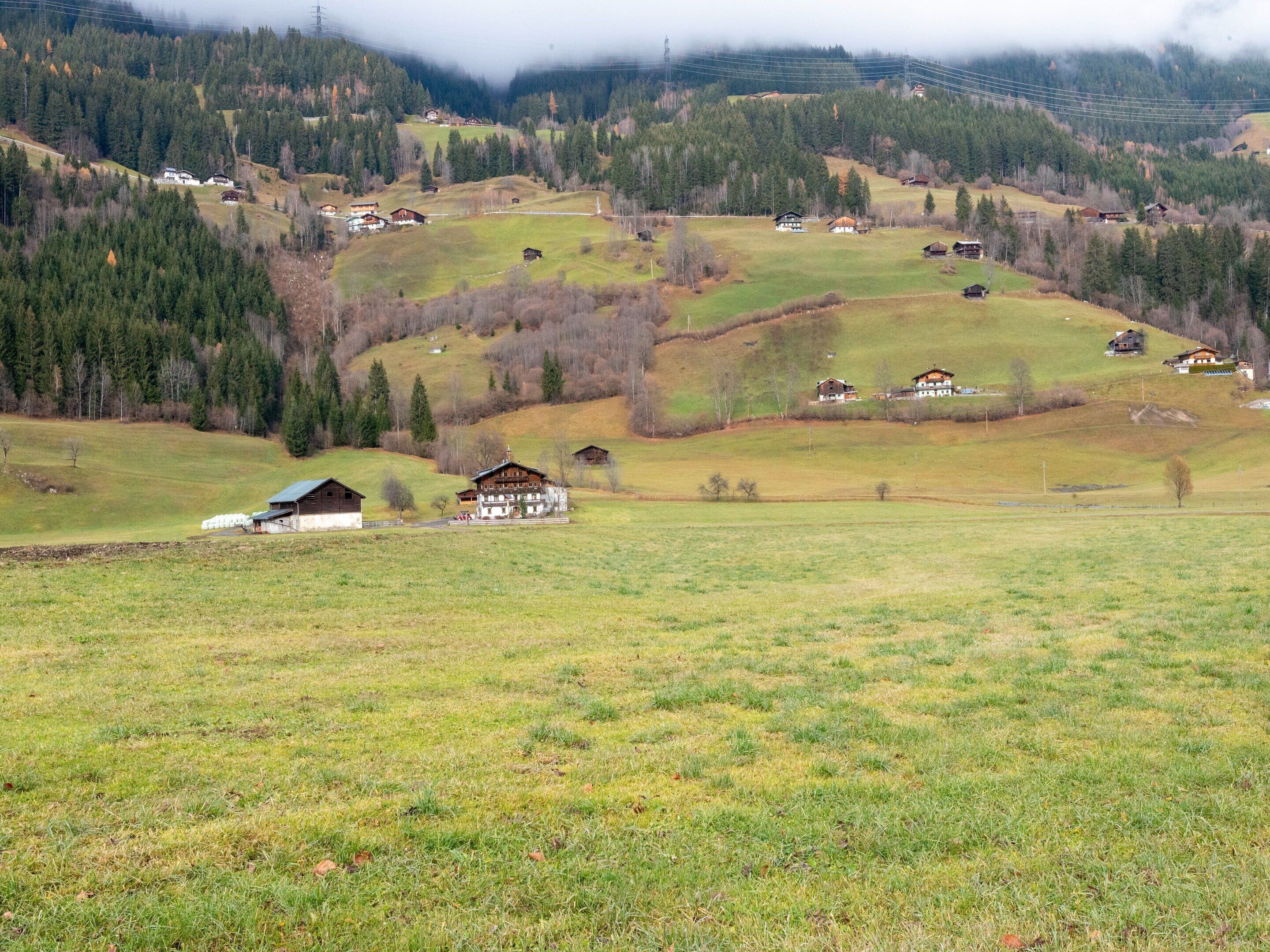 Paesaggio rurale con case sparse, un edificio importante con un ampio balcone e un terreno collinare.