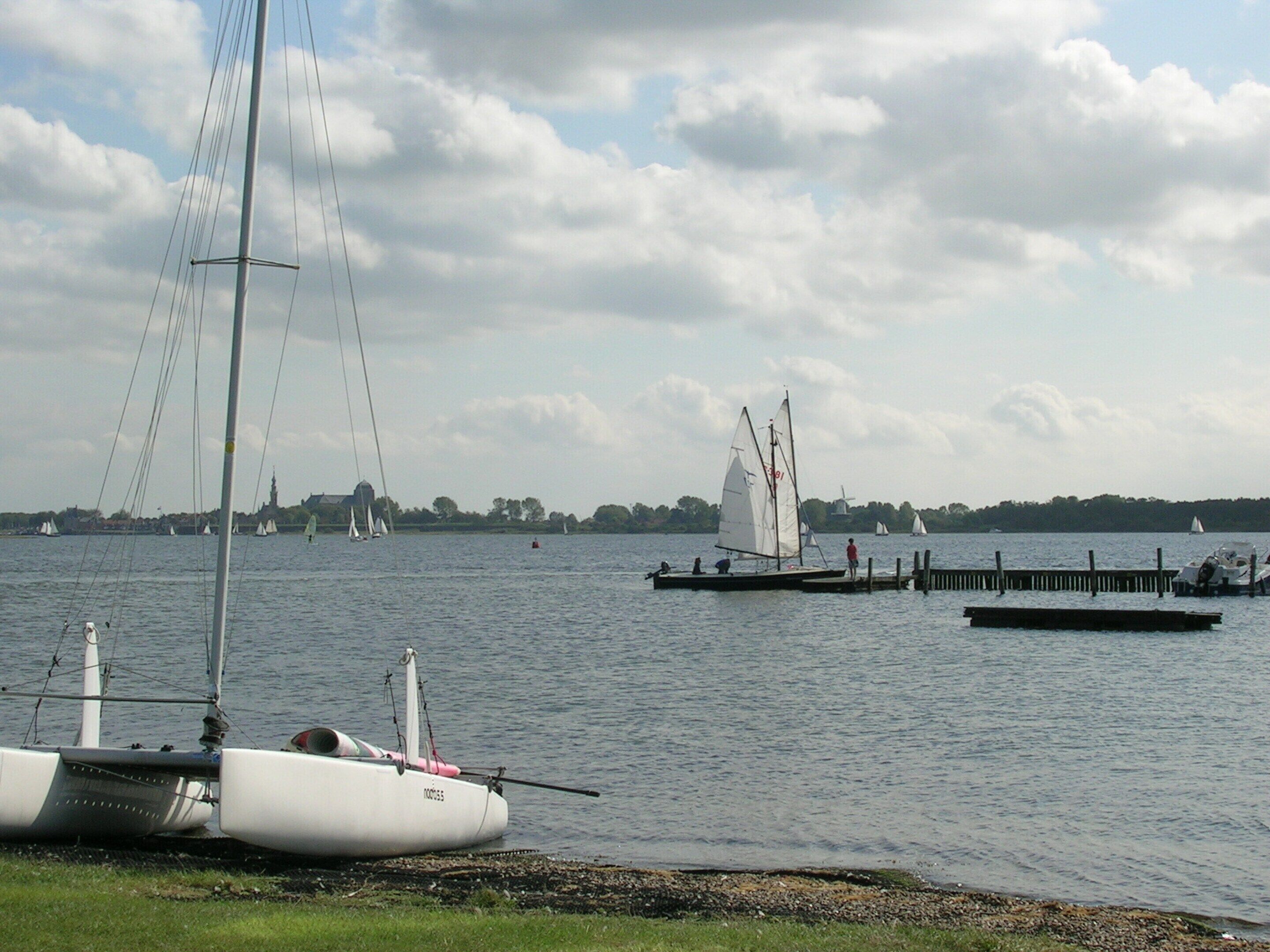A calm lake with sailboats and a dock.