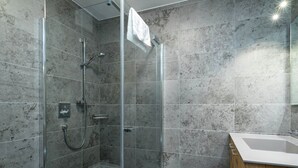 A modern bathroom with a glass-enclosed shower, a white bathtub, and a wooden vanity. - Apartment in Hollersbach With Sauna Near ski Area (Hollersbach im Pinzgau)