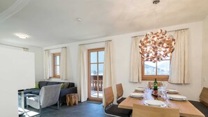A modern dining area with a wooden table and chairs, a sofa, and a view of the outdoors. - Apartment in Hollersbach With Sauna Near ski Area (Hollersbach im Pinzgau)