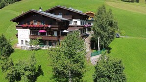 Un'ampia chalet a più piani con balconi, immersa in prati verdi e alberi rigogliosi.