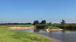 A calm river with grassy banks and trees in the background. - Appealing Holiday Home in Guelders near Forest (Lochem)
