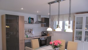 A modern kitchen with a dining table, chairs, and pendant lights. - Holiday Home with Garden & Terrace near Rennsteig in Thuringian Forest (Waltershausen)