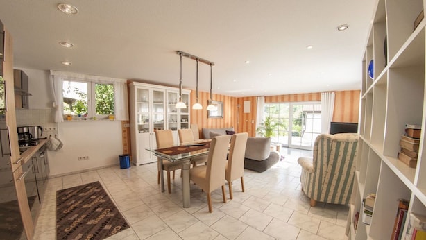 A spacious living area with a dining table, chairs, a sofa, and a bookshelf. - Holiday Home with Garden & Terrace near Rennsteig in Thuringian Forest (Waltershausen)