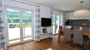 A modern living room with a TV, dining area, and kitchen.