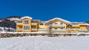 A yellow multi-story hotel with balconies, set against a snowy landscape and a clear blue sky.