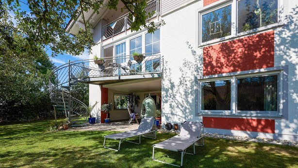 A two-story building with a balcony, outdoor seating, and a well-maintained lawn. - Apartment With Sauna (Zandt)