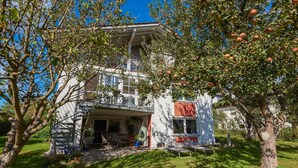 A two-story house with a balcony, a spiral staircase, and a garden with a tree bearing fruit. - Apartment With Sauna (Zandt)