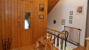 A wooden interior with a wooden staircase, a rocking horse, and framed pictures on the walls. - Ferienhaus in Saldenburg mit Sauna (Saldenburg)