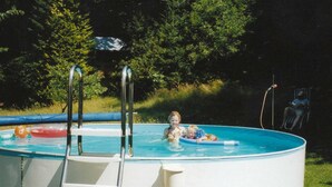 A swimming pool with a ladder, surrounded by trees. - Ferienhaus in Saldenburg mit Sauna (Saldenburg)