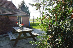 Een picknicktafel met een bloemstuk voor een bakstenen gebouw met een raam.