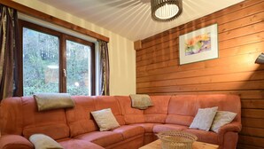 A cozy living room with a sectional sofa, a small table, and a window with curtains. - Family Villa With Garden (Bouillon)