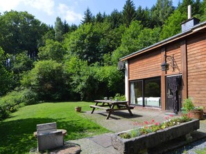 Eine Holzhütte mit Terrasse, Satellitenschüssel und großem Fenster.