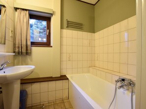 Et badeværelse med vask, vindue og badekar.