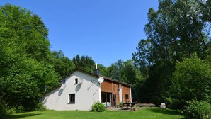 A single-story house with a sloped roof, satellite dishes, and a wooden deck. - Family Villa With Garden (Bouillon)