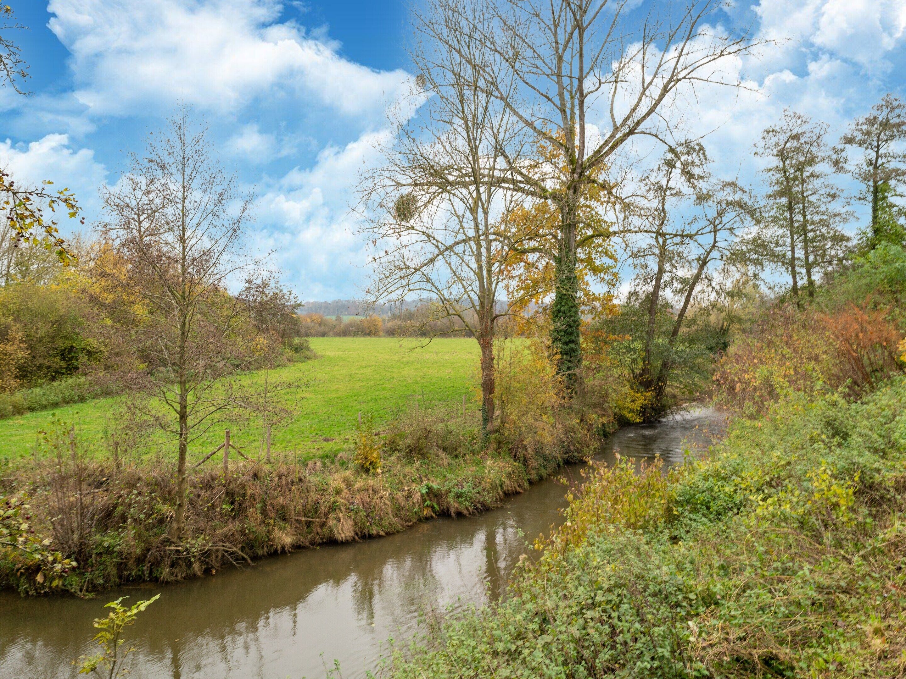 A river flowing through a rural landscape with trees and open fields.