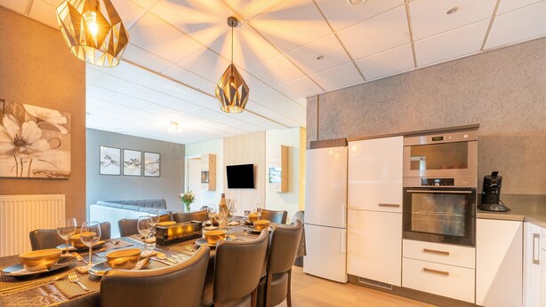 Una cocina moderna con horno empotrado, refrigerador y comedor con mesa dispuesta para cuatro.
