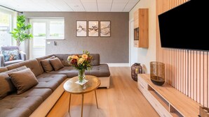Una sala de estar moderna con un sofá, una mesa de centro y un televisor de pantalla plana montado en una pared de madera.