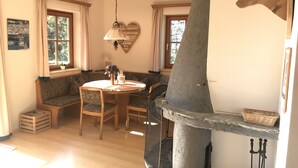 A cozy dining area with a round table, wooden chairs, and a bench. A stone chimney with a heart-shaped decoration is visible. - Boutique Chalet in Maria Alm near Hochkönig (Maria Alm am Steinernen Meer)