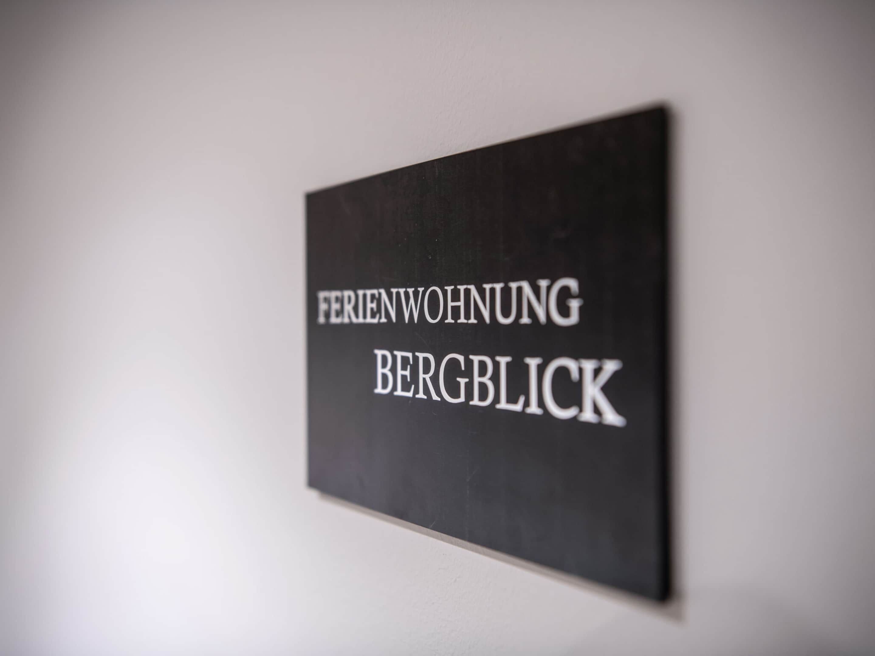 A sign with the text "FERIENWOHNUNG BERGBLICK" on a wall.