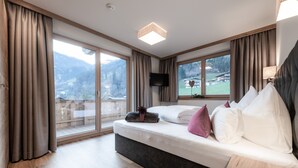 A bedroom with a large bed, a TV, and a view of mountains. - Farmhouse in Schwendau With Balcony (Schwendau)
