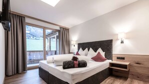 A modern bedroom with a large bed, a wooden headboard, a nightstand, and a window with curtains. - Farmhouse in Schwendau With Balcony (Schwendau)