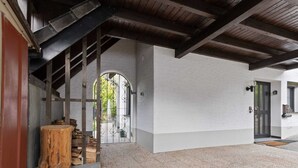 Un espacio al aire libre cubierto con piso de baldosas, un tocón de madera y una reja metálica que da a una escalera.