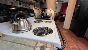A kitchen with a white stove, a kettle, and a black range hood. - Casita I - 2 Bed, 2 Bath (Santa Fe)